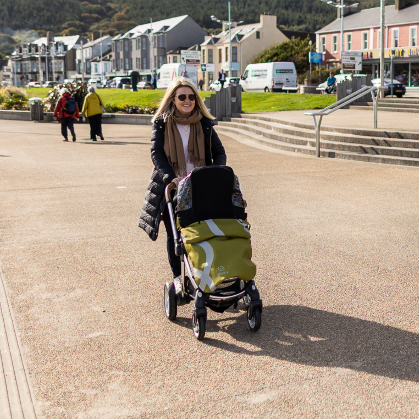 Lady pushing stroller with sun shade up using BlinkyWarm in Olive