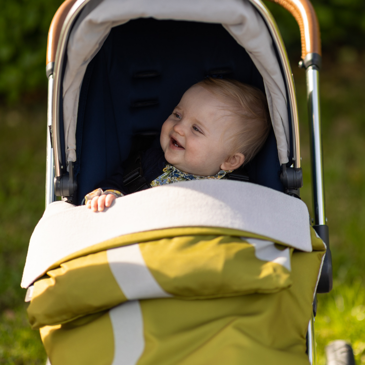Baby smiling in stroller with BlinkyWarm in Olive